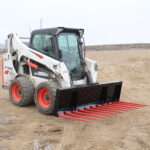 Angled side view of a skid steer loader showcasing Messer Attachments heavy-duty manure fork with spring steel tines