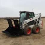 Left side view with opened grapples, on skid loader 68 inch Rock Bucket with Grapple by Messer Attachments fits skid loader, wheel loaders, crawl loaders, front loaders. Compatible with John Deere, Bobcat, Case, New Holland, Kubota,