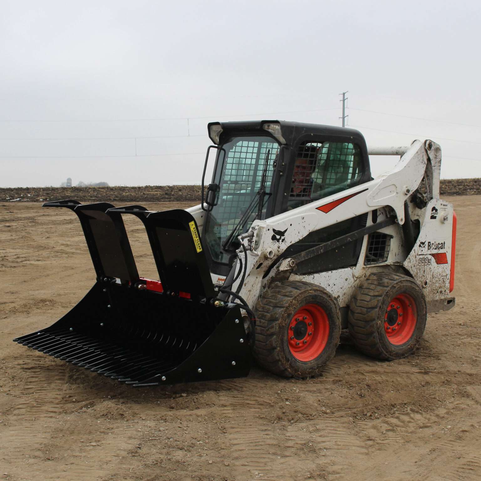 Left side view with opened grapples, on skid loader 68 inch Rock Bucket with Grapple by Messer Attachments fits skid loader, wheel loaders, crawl loaders, front loaders. Compatible with John Deere, Bobcat, Case, New Holland, Kubota,