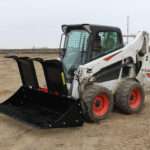 Left side view with opened grapples, on skid loader 75 inch Rock Bucket with Grapple by Messer Attachments fits skid loader, wheel loaders, crawl loaders, front loaders. Compatible with John Deere, Bobcat, Case, New Holland, Kubota, JCB