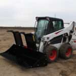 Left side view with opened grapples, on skid loader 88 inch Rock Bucket with Grapple by Messer Attachments fits skid loader, wheel loaders, crawl loaders, front loaders. Compatible with John Deere, Bobcat, Case, New Holland, Kubota, JCB, Caterpillar